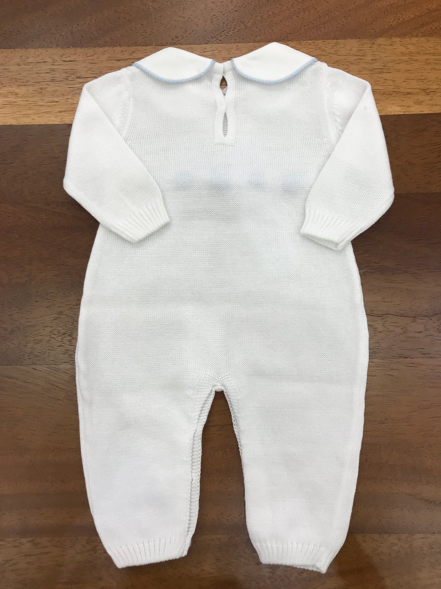 Tutina Baby Lord in filo bianco manica lunga con collo tondo rifinito in celeste con fiocco applicato sul centro con passanastro