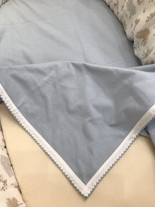 Coperta Martin Aranda in cotone celeste polvere con bordo rifinito in bianco e ricamo celeste