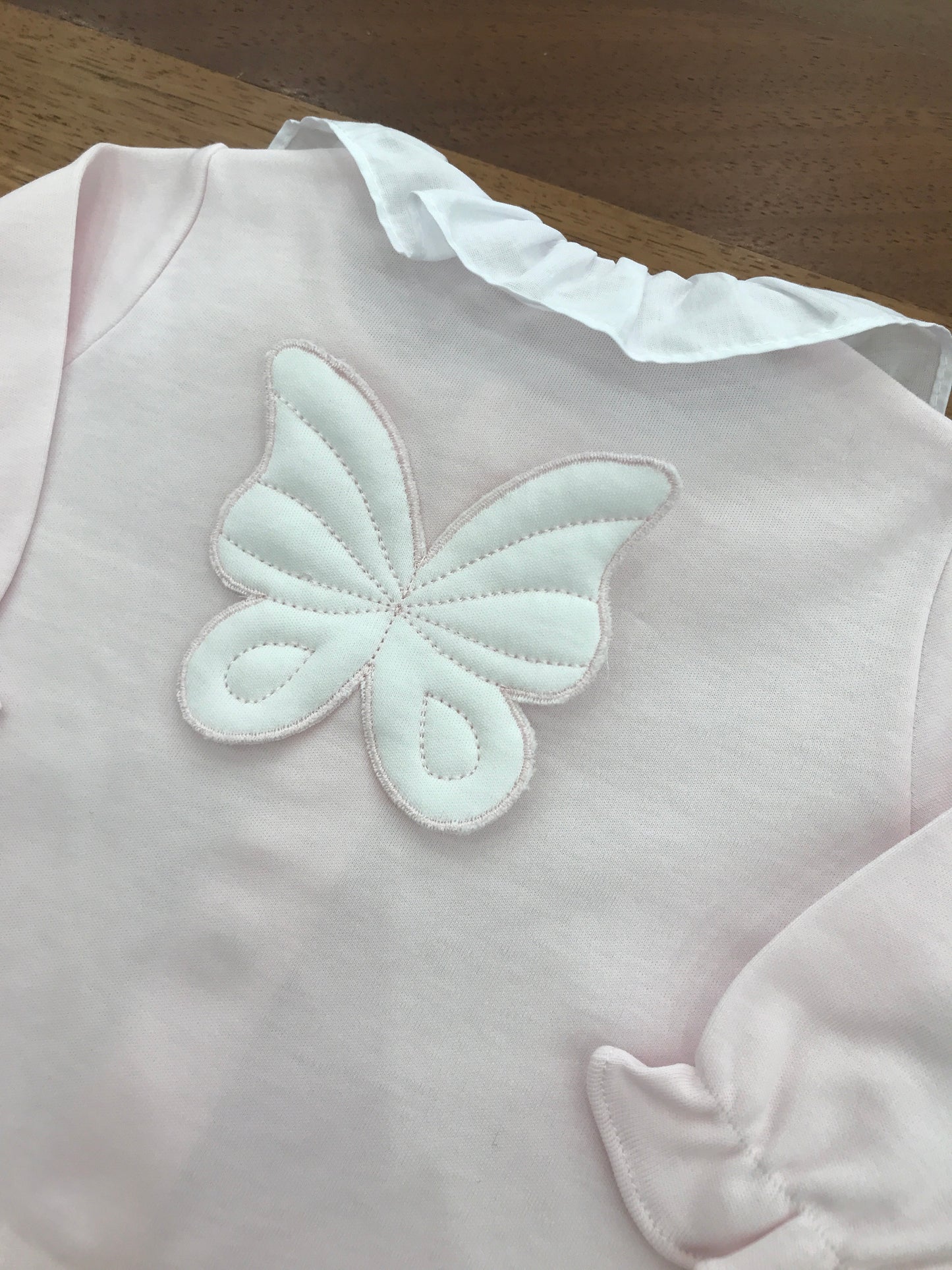 Tutina Baby Gi in cotone con piedini manica lunga con collo con rusche bianca sul retro applicata una farfalla