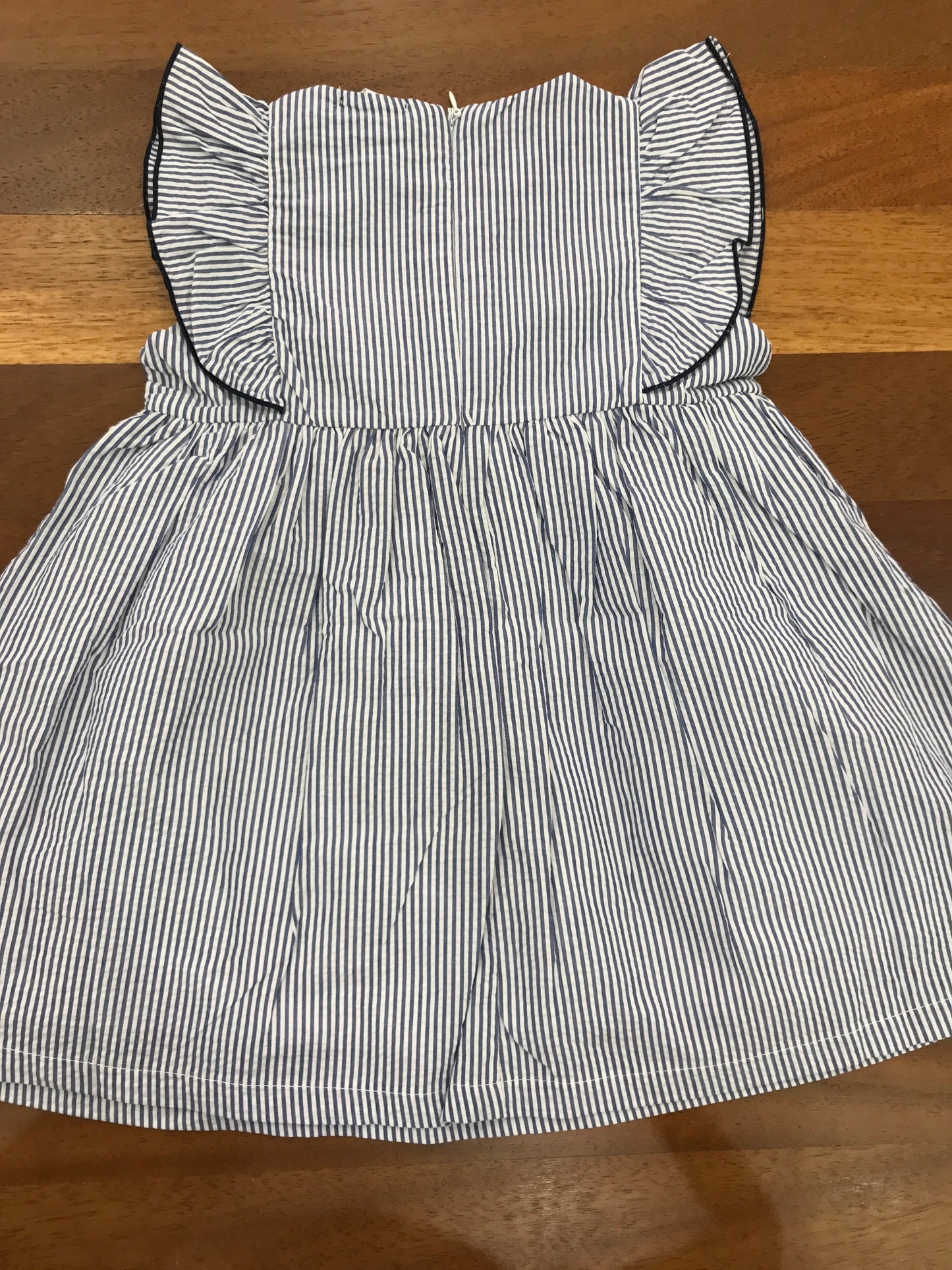 Abito Nanan in cotone smanicato a righe blu e bianche con rusche con fiocco blu scuro sul davanti e zip sul retro