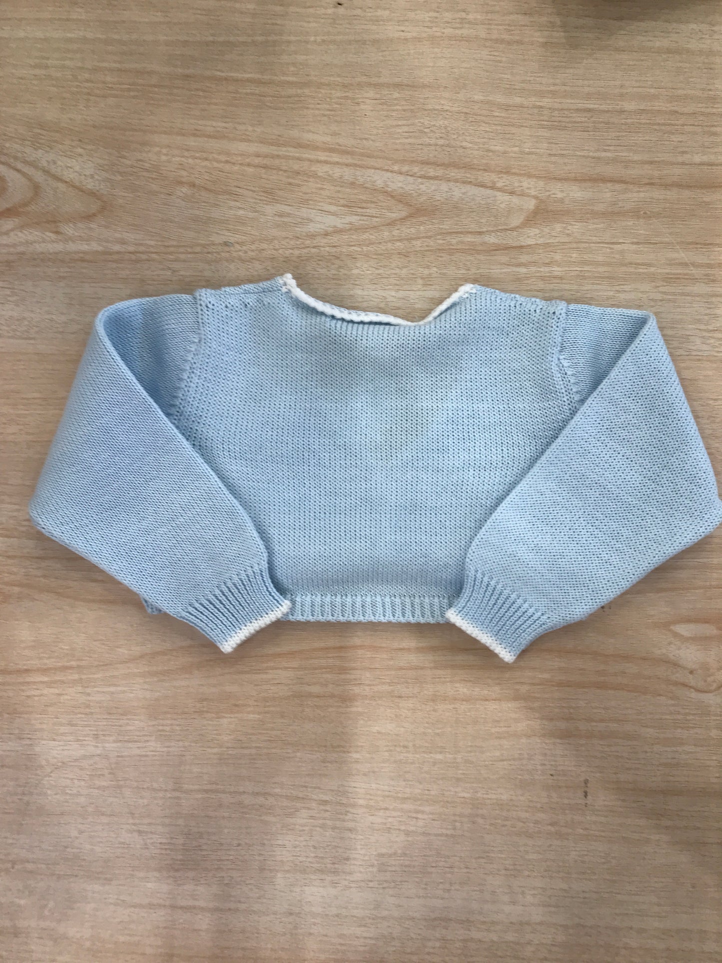 Cardigan Bebè di Almy in filo celeste rifinito in bianco con piccoli bottoncini sul davanti