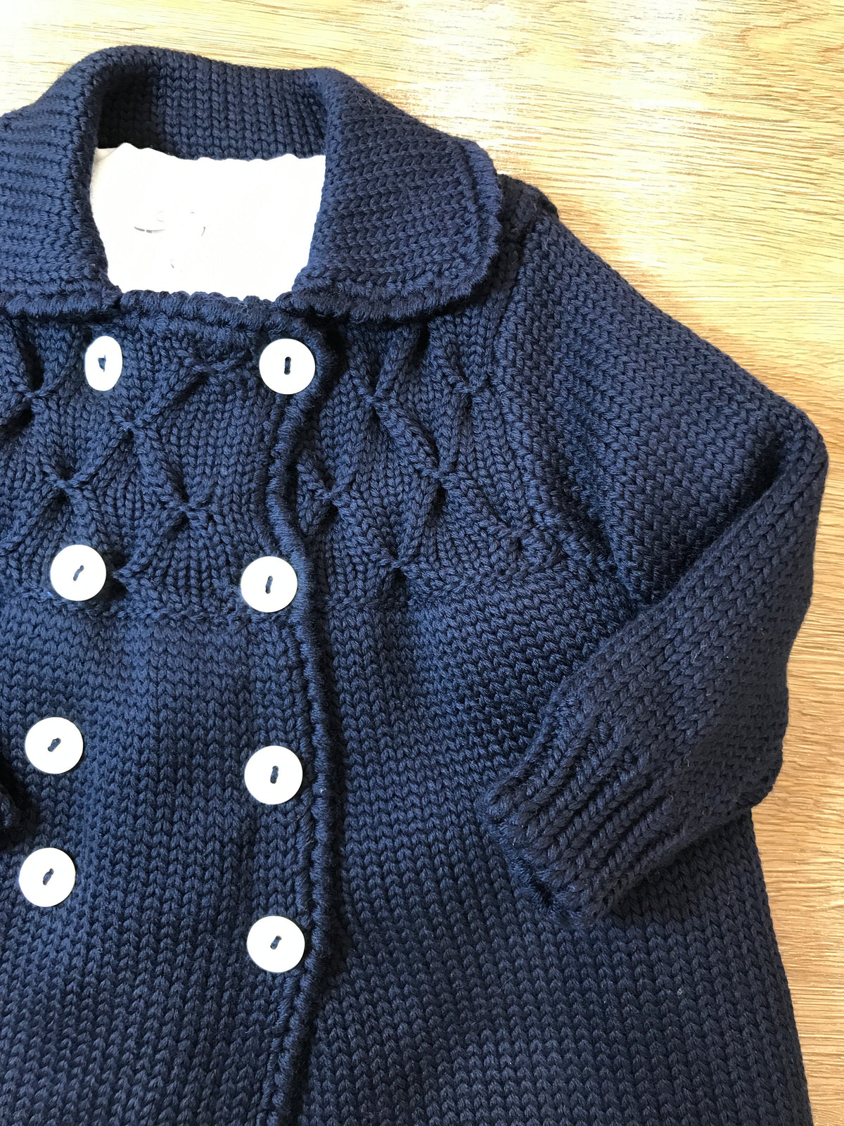 Cappotto Colibrì in lana foderato con piccoli bottoncini doppiopetto e lavorazione di punto smock
