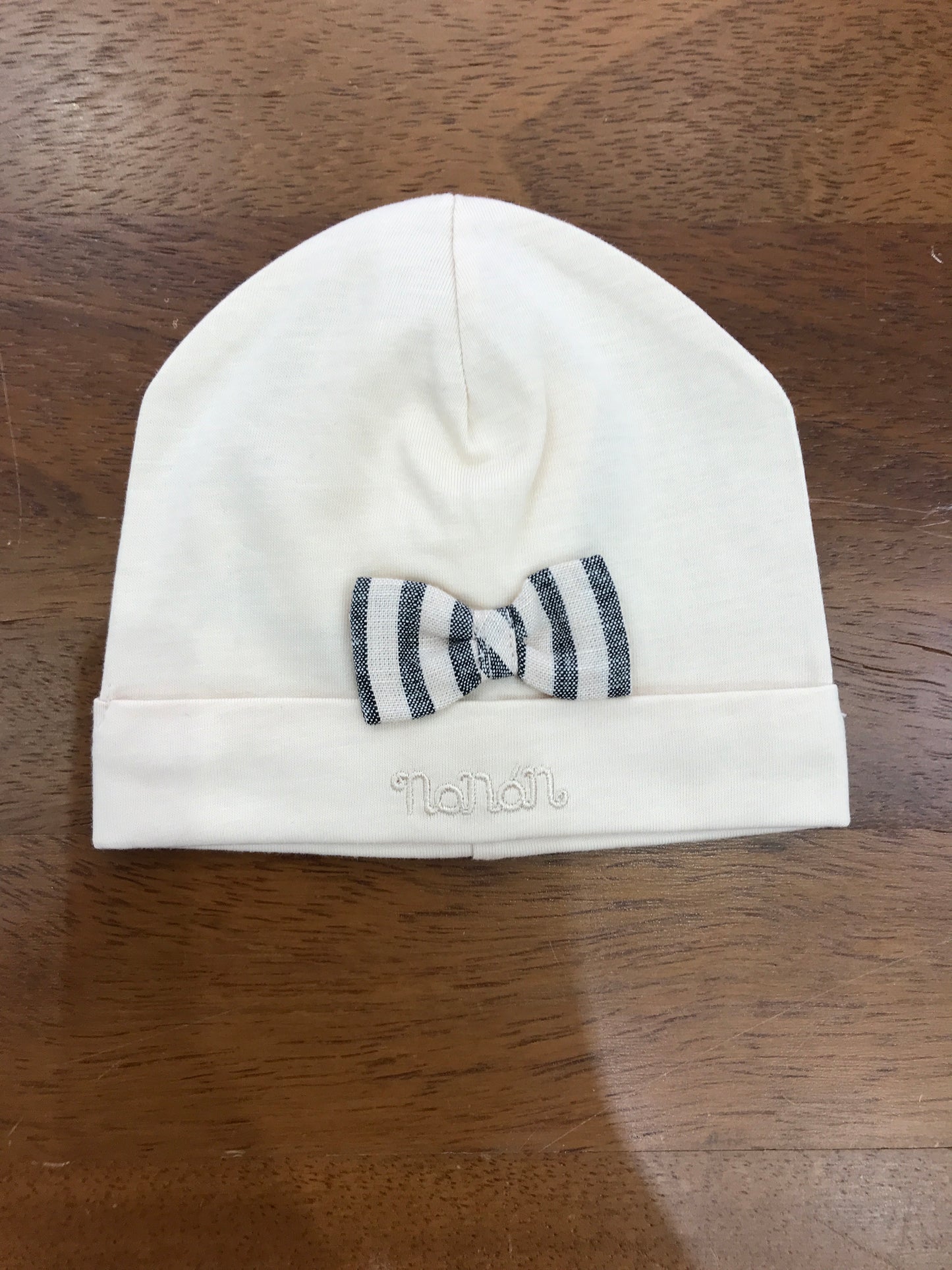 Cappello Nanan in cotone beige con risvolto e fiocchetto sul davanti