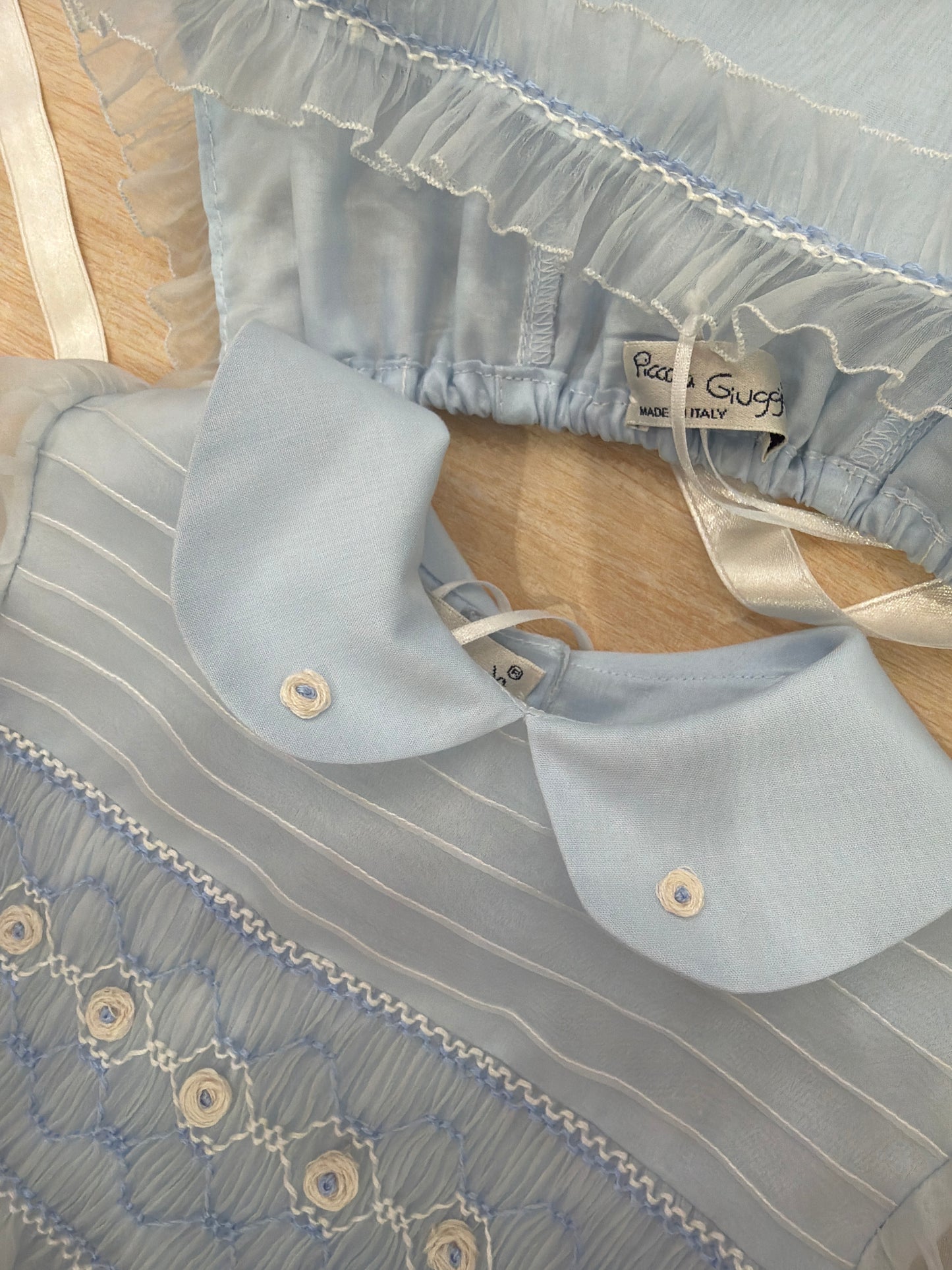 Abito Piccola Giuggiola in organza in seta celeste mezza manica con lavorazione di punto smock e lavorazione di fiori con cuffietta abbinata