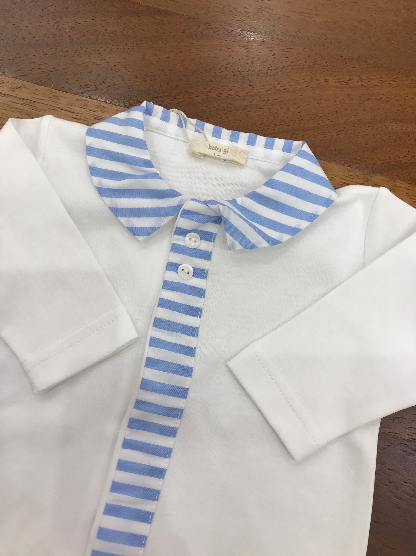 Tutina Baby Gi in cotone bianca maniche lunghe gamba lunga con piedini collo a righe bianche e celesti con dettagli che scende sul davanti