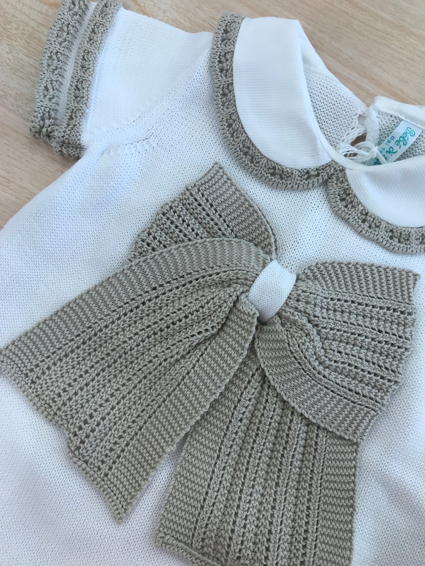 Pagliaccetto Bebè di Almy in filo bianco con rifiniture in tortora con fiocco centrale sul davanti