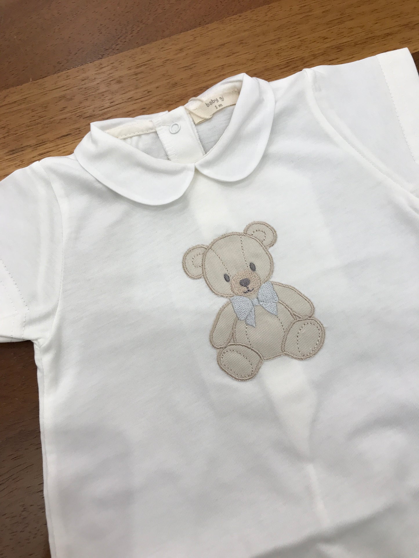 Pagliaccetto Baby Gi in cotone panna corto mezza manica con collo tondo con orsetto centrale sul davanti con fiocchetto