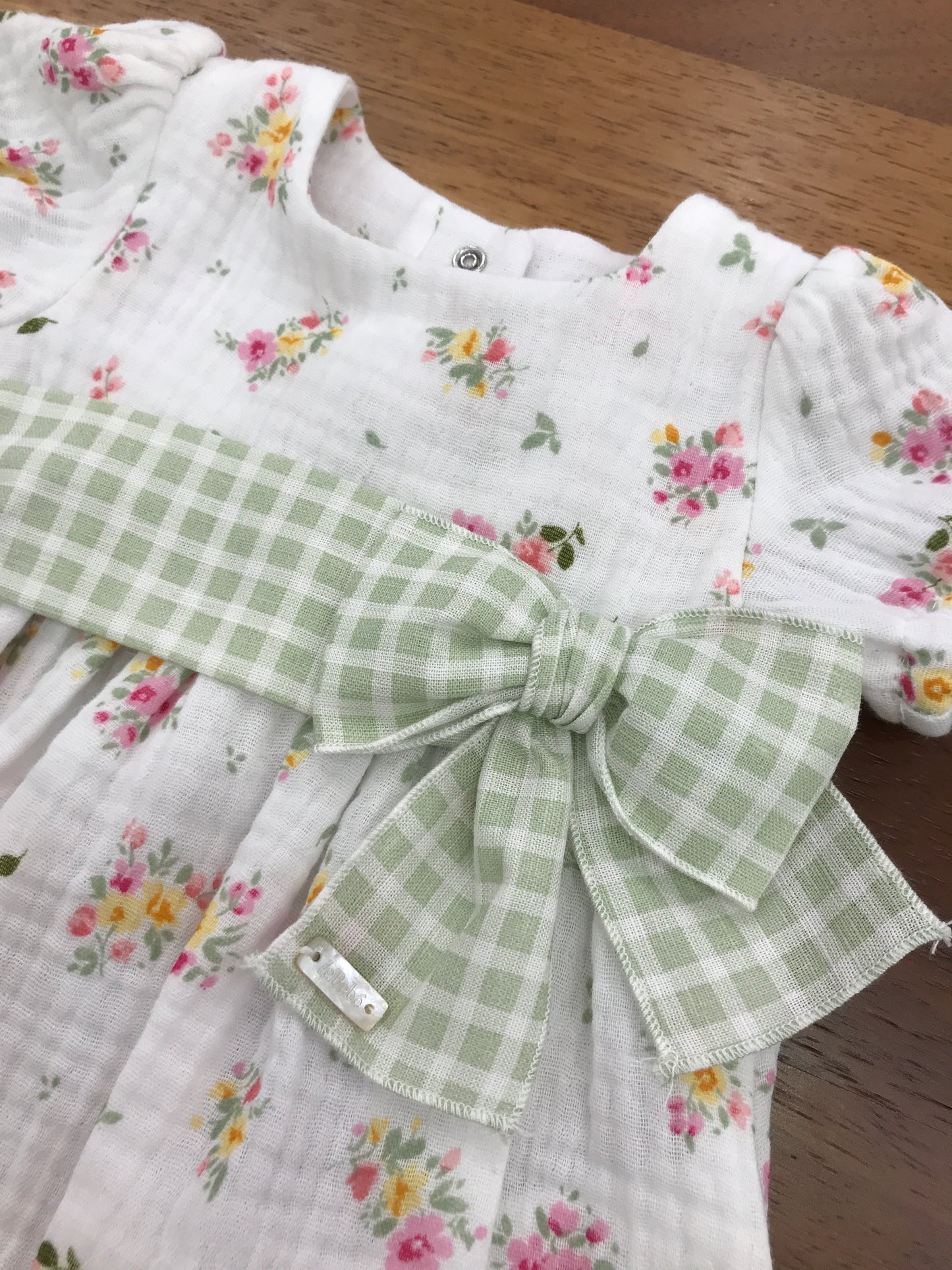 Pagliaccetto Le Bebè in mussola di cotone manica a sbuffo con fiorellini ricamati con fascia a quadretti bianchi e verdi con fiocco