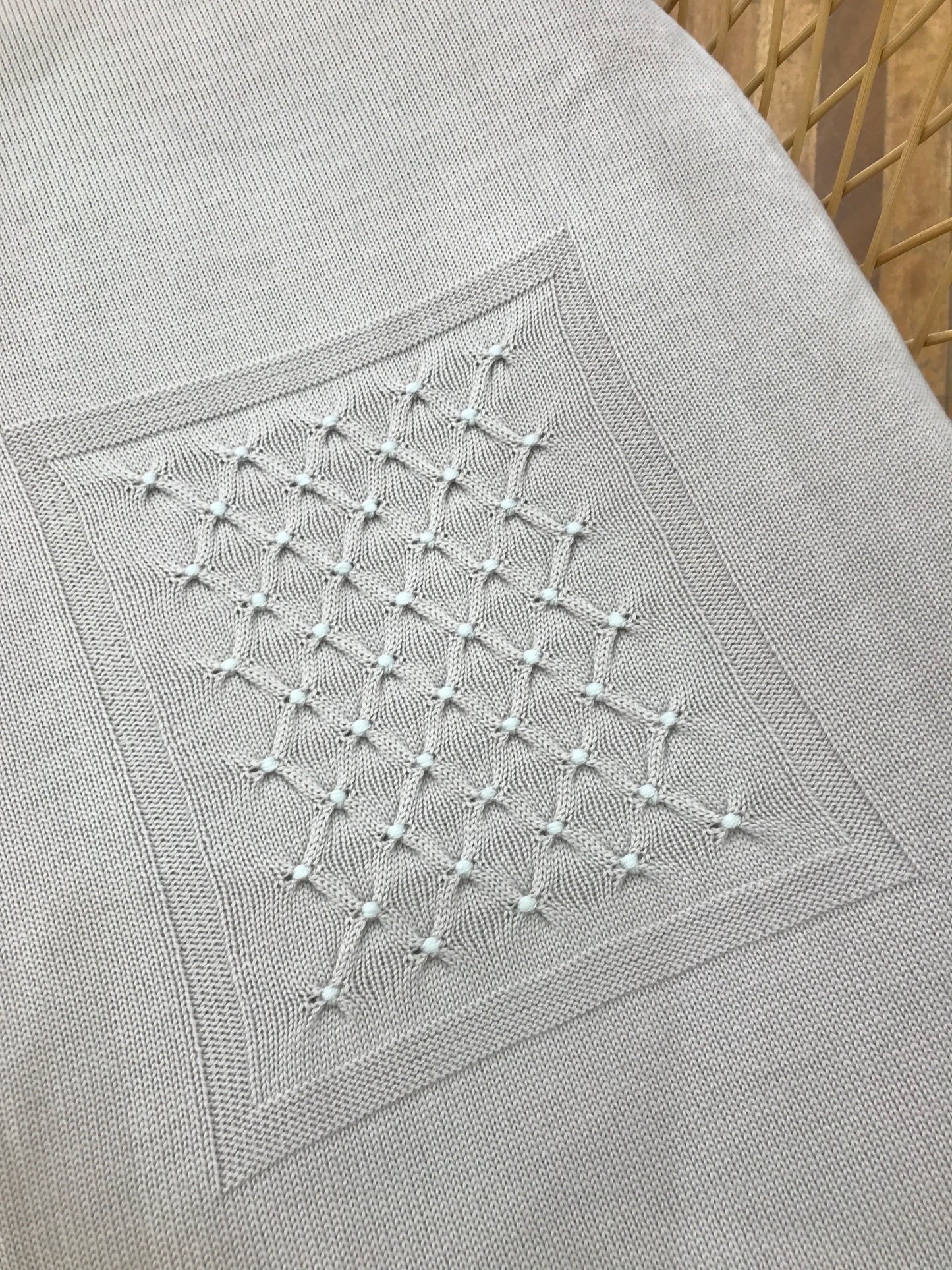 Coperta Baby Lord in lana color sabbia con punto smock celeste ricamato al centro di un riquadro centrale