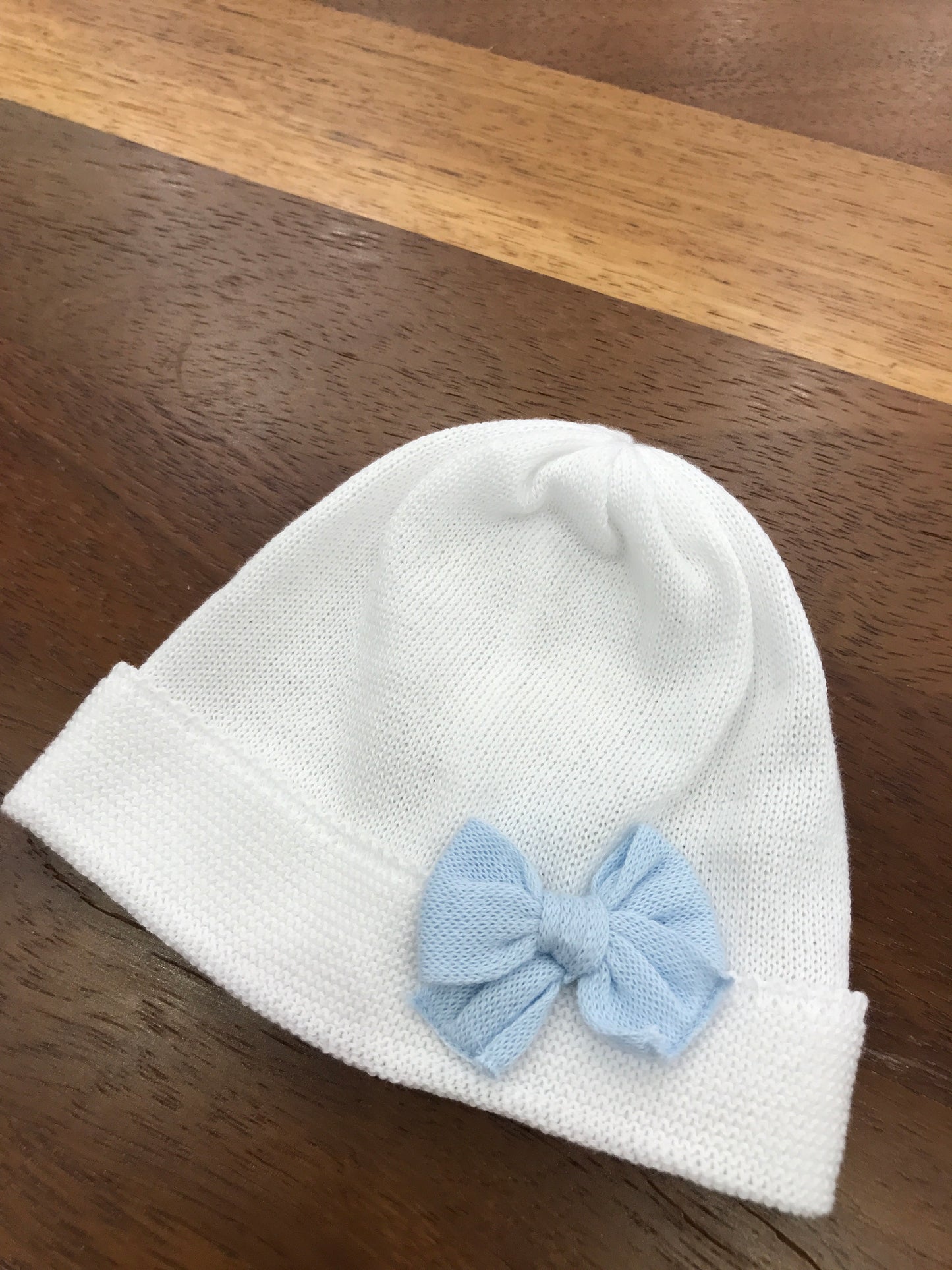 Cappello Baby Lord in filo bianco con risvolto con fiocco celeste applicato sul davanti