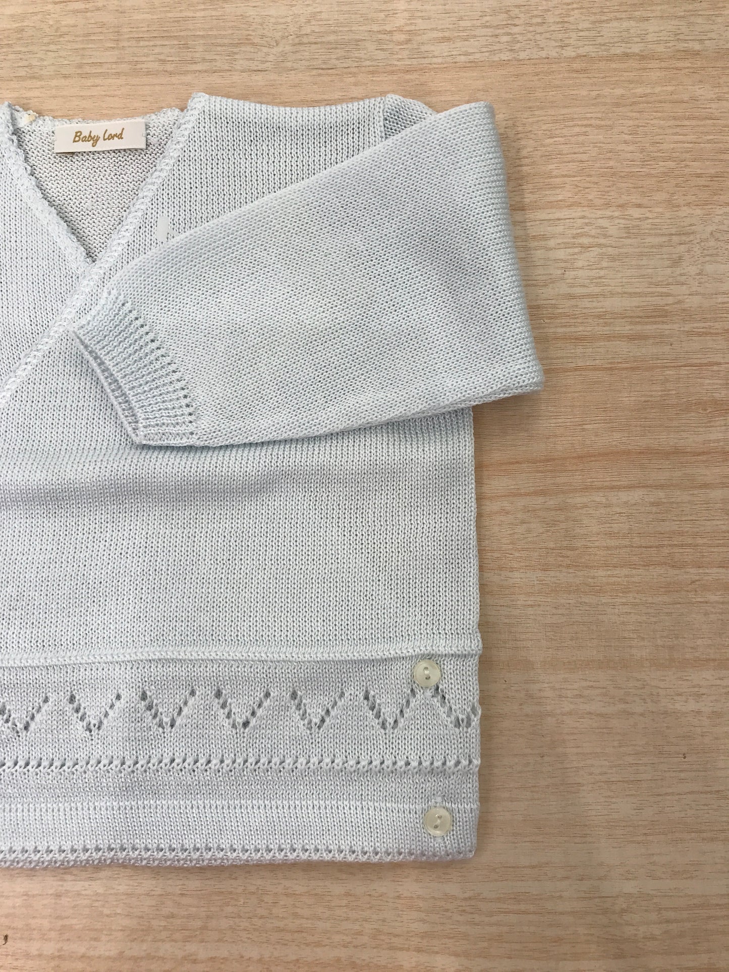 Cardigan Baby Lord in filo celeste chiaro ad incrocio con lavorazioni in basso