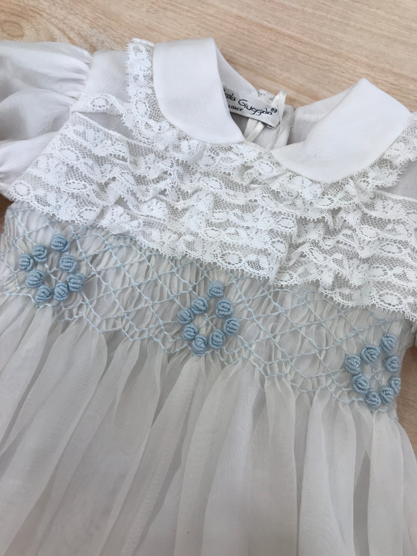 Pagliaccetto Piccola Giuggiola in organza in seta bianco mezza manica a sbuffo con applicazioni di valancienne e piccole rose celesti ricamate