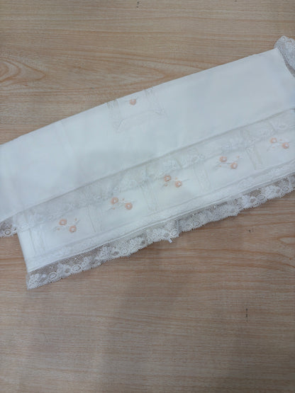Lenzuolino Piccola Giuggiola in battista di cotone bianco con rifiniture in pizzo piccoli riquadri con roselline rosa ricamate