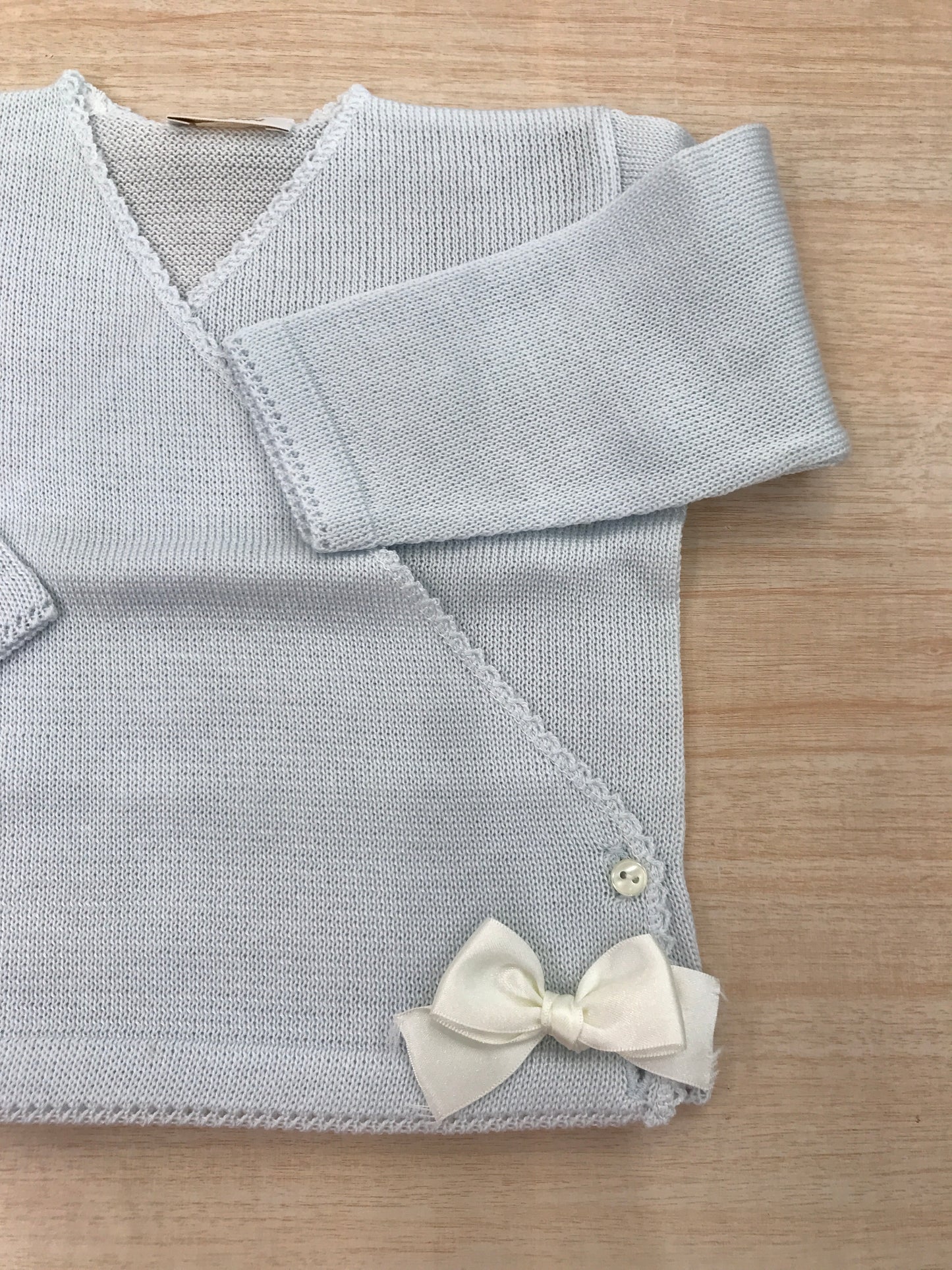 Cardigan Baby Lord in filo celeste ad incrocio con fiocchetti bianchi