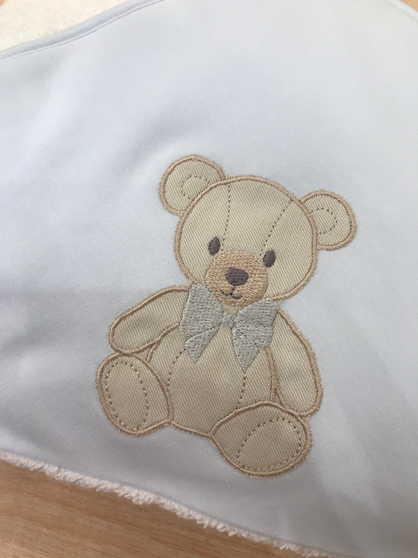 Telo Bagnetto Baby Gi in spugna con bordo celeste con triangolo celeste con orsetto ricamato con fiocchetti grigio