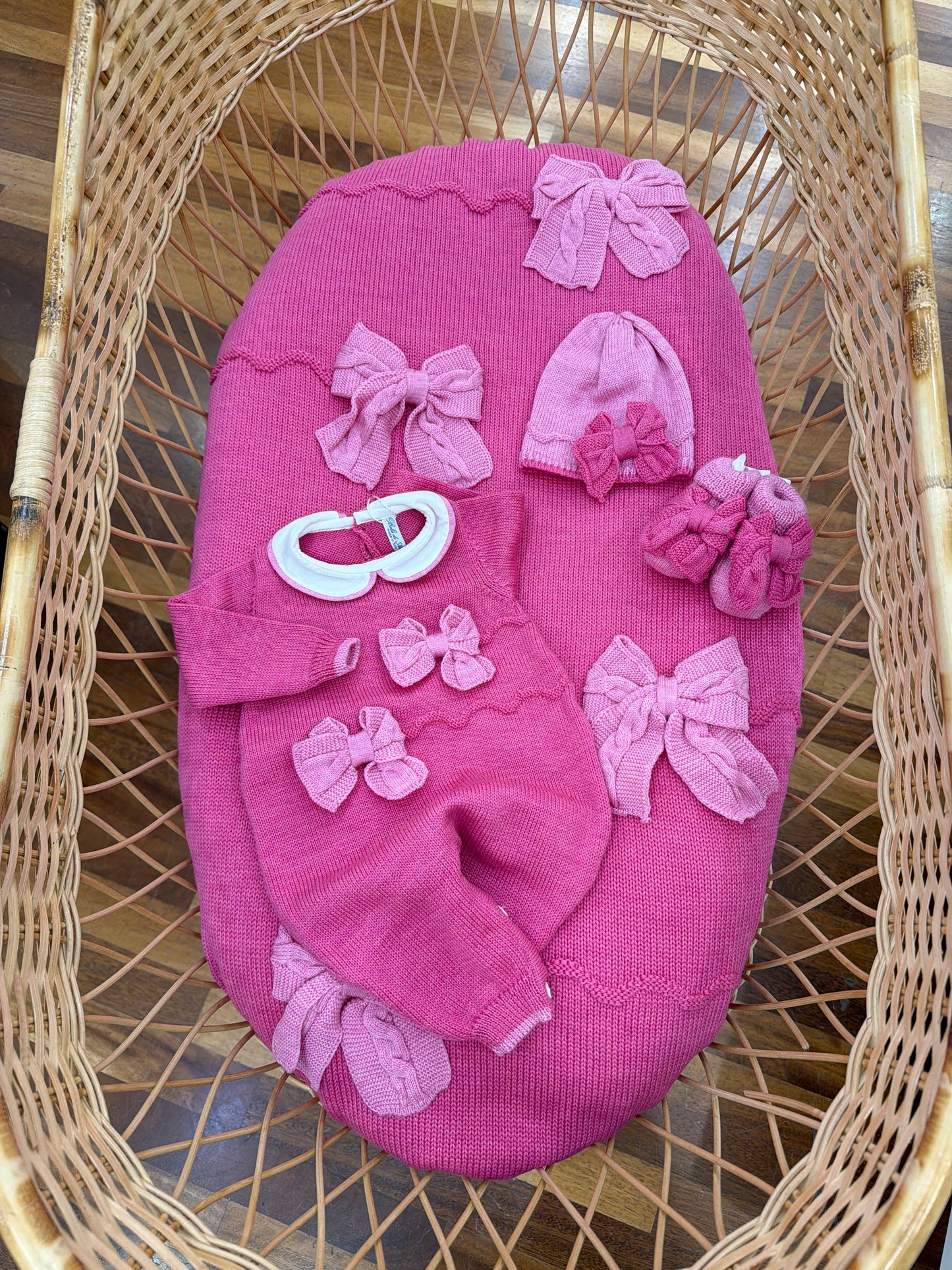 Coordinato nascita Bebè di Almy in lana fucsia con fiocchi rosa in rilievo applicati sul davanti di coperta tutina cappello e babbucce sono l'inverso