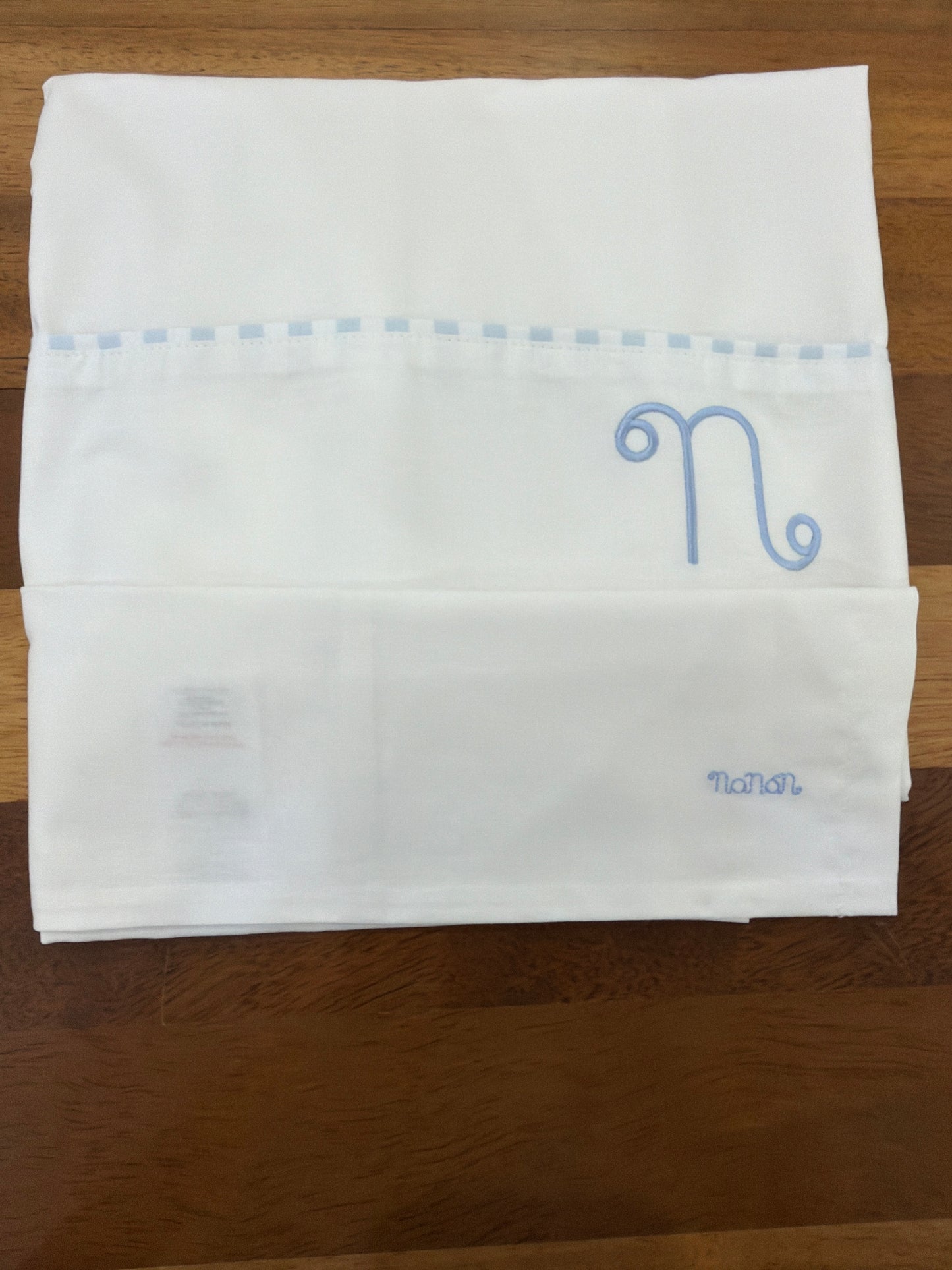 Lenzuolino Nanan bianco in cotone con logo nanan su federa con passanastro celeste