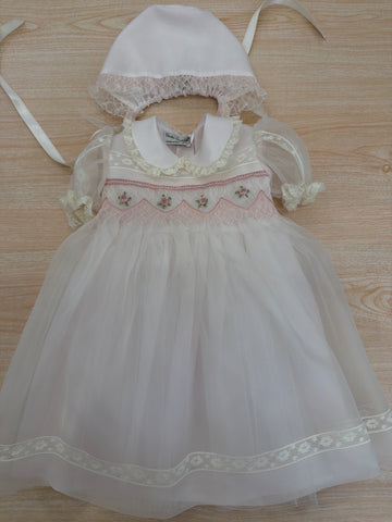 Abito Piccola Giuggiola in organza in seta rosa con applicazione di pizzo sul gonnellone e corpetto con lavorazione di punto smock e fiori ricamati con cuffietta abbinata