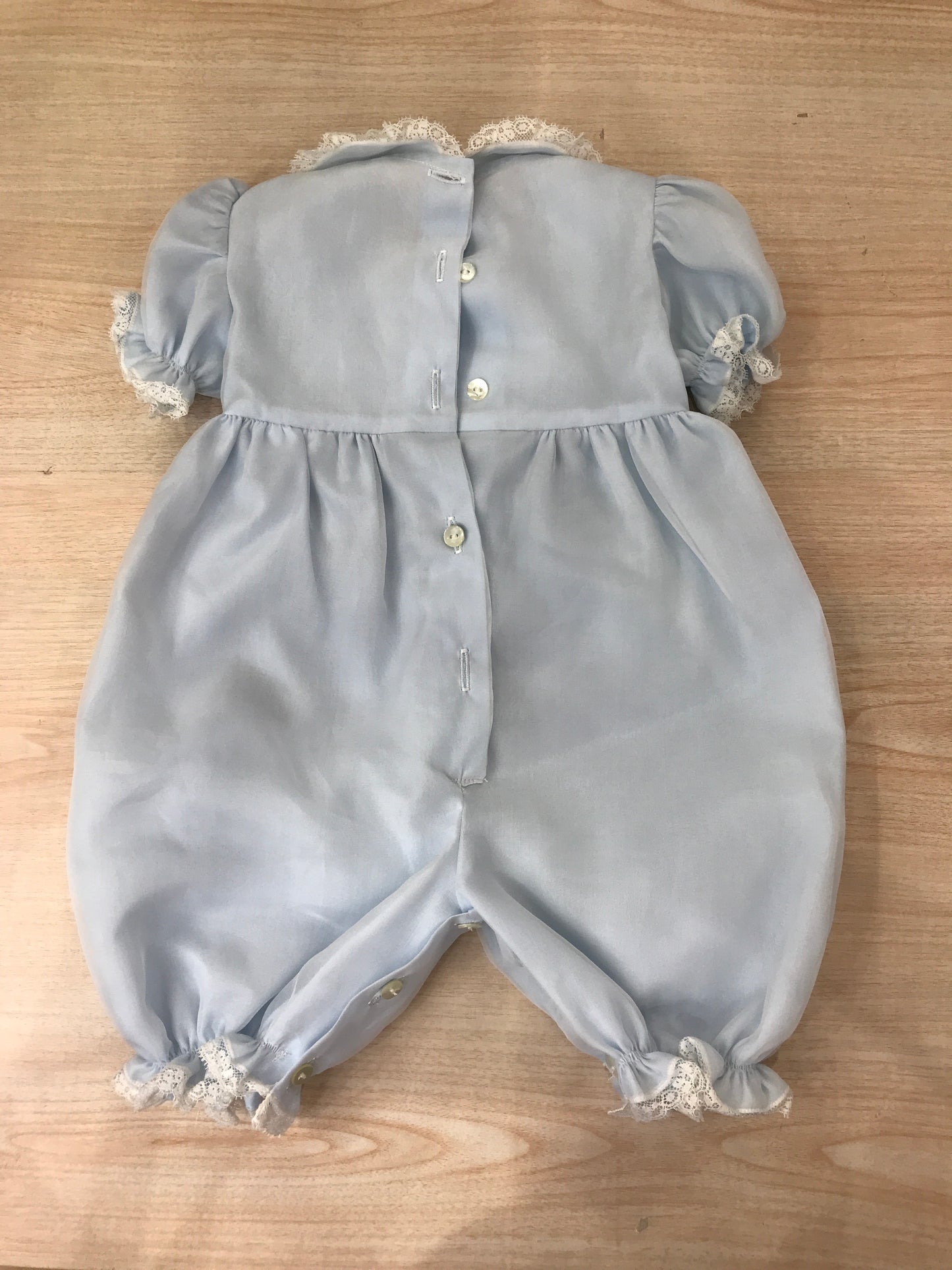 Pagliaccetto Piccola Giuggiola in organza in seta celeste manica a sbuffo con applicazone di valancienne corpetto rifinito da punto smock con fiocco centrale