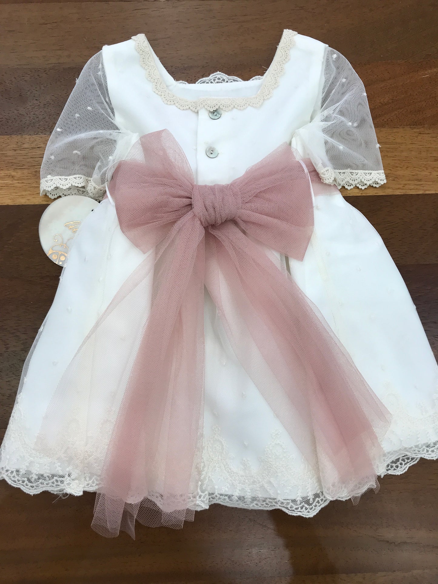 Abito Lilus in cotone mezza manica velata in tulle con pizzo lavorato sul corpetto e sul gonnellone con cintura in tulle rosa con fiori applicati al centro