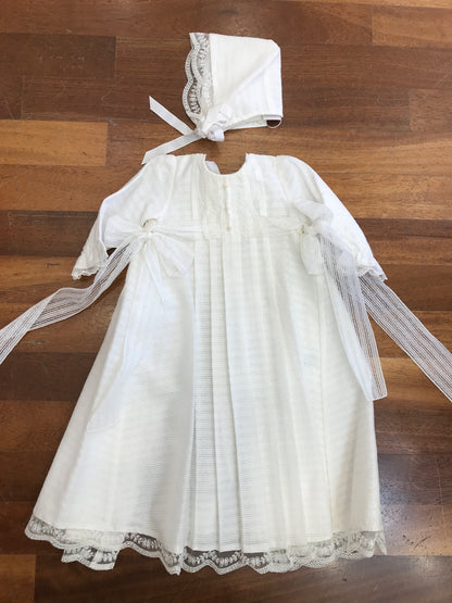 Abito lungo Paz Rodriguez in battista di cotone manica lunga con fiocchetti laterali pizzo e cuffietta coordinata