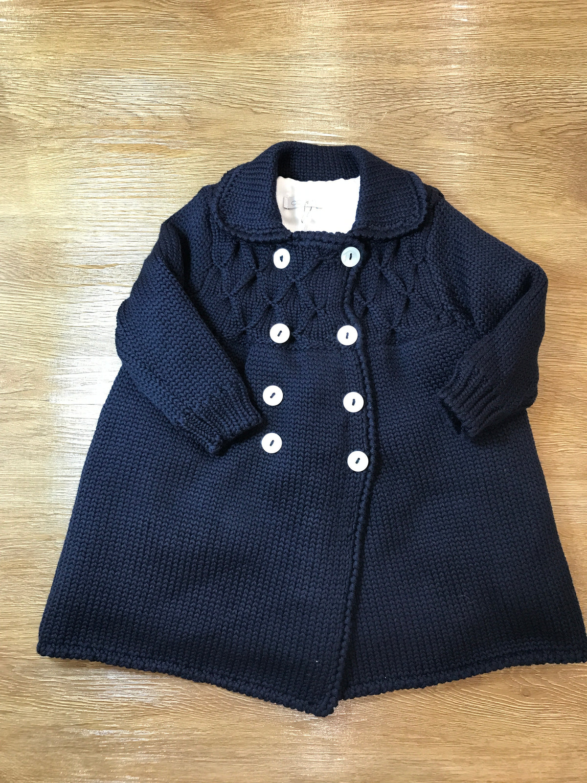 Cappotto Colibrì in lana foderato con piccoli bottoncini doppiopetto e lavorazione di punto smock