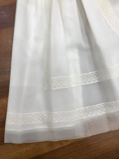 Abito Belan in battista di cotone e organza in seta con lavorazione di pizzo applicato sulla gonna e sulla fascia in vita