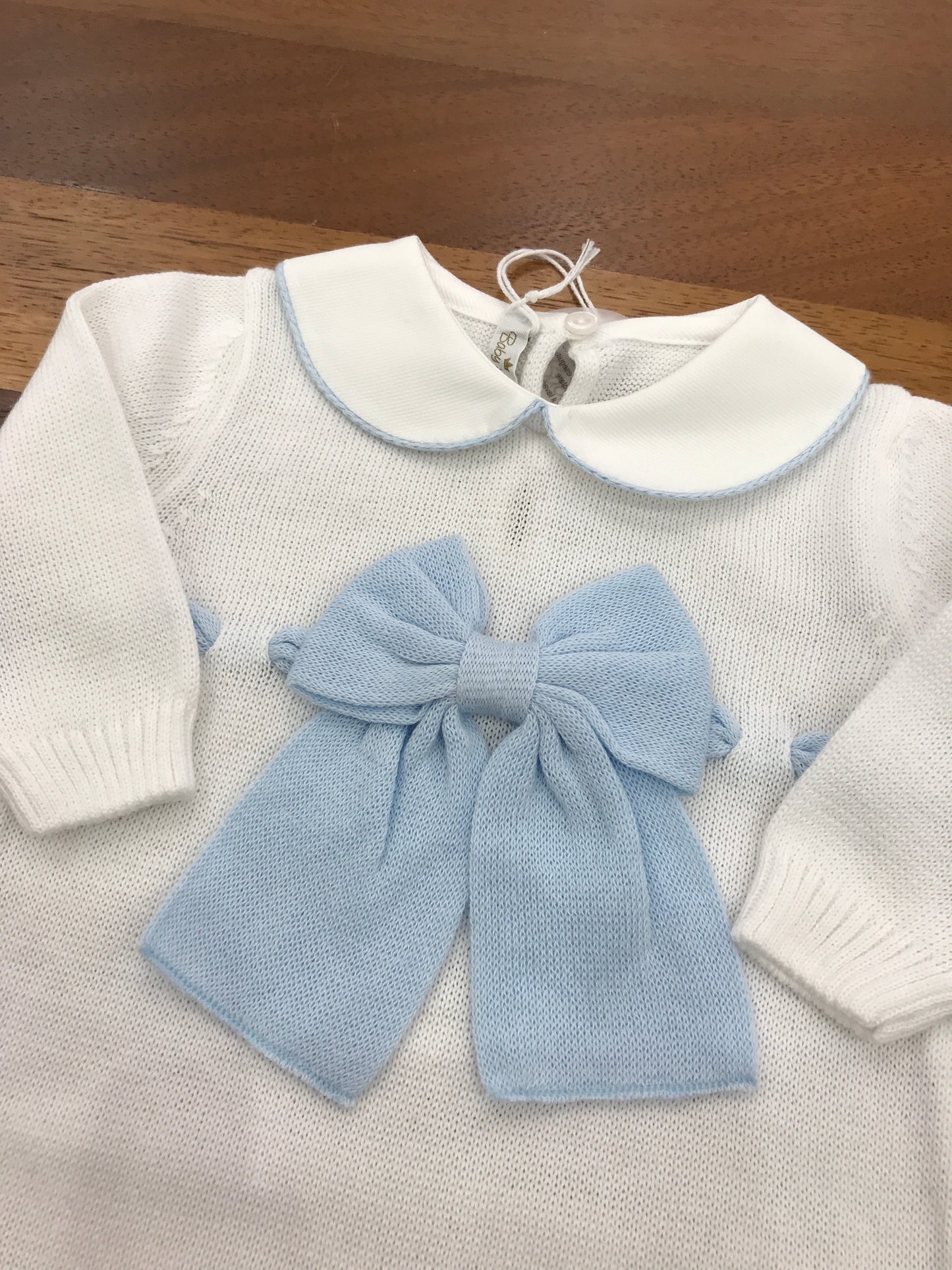 Tutina Baby Lord in filo bianco manica lunga con collo tondo rifinito in celeste con fiocco applicato sul centro con passanastro