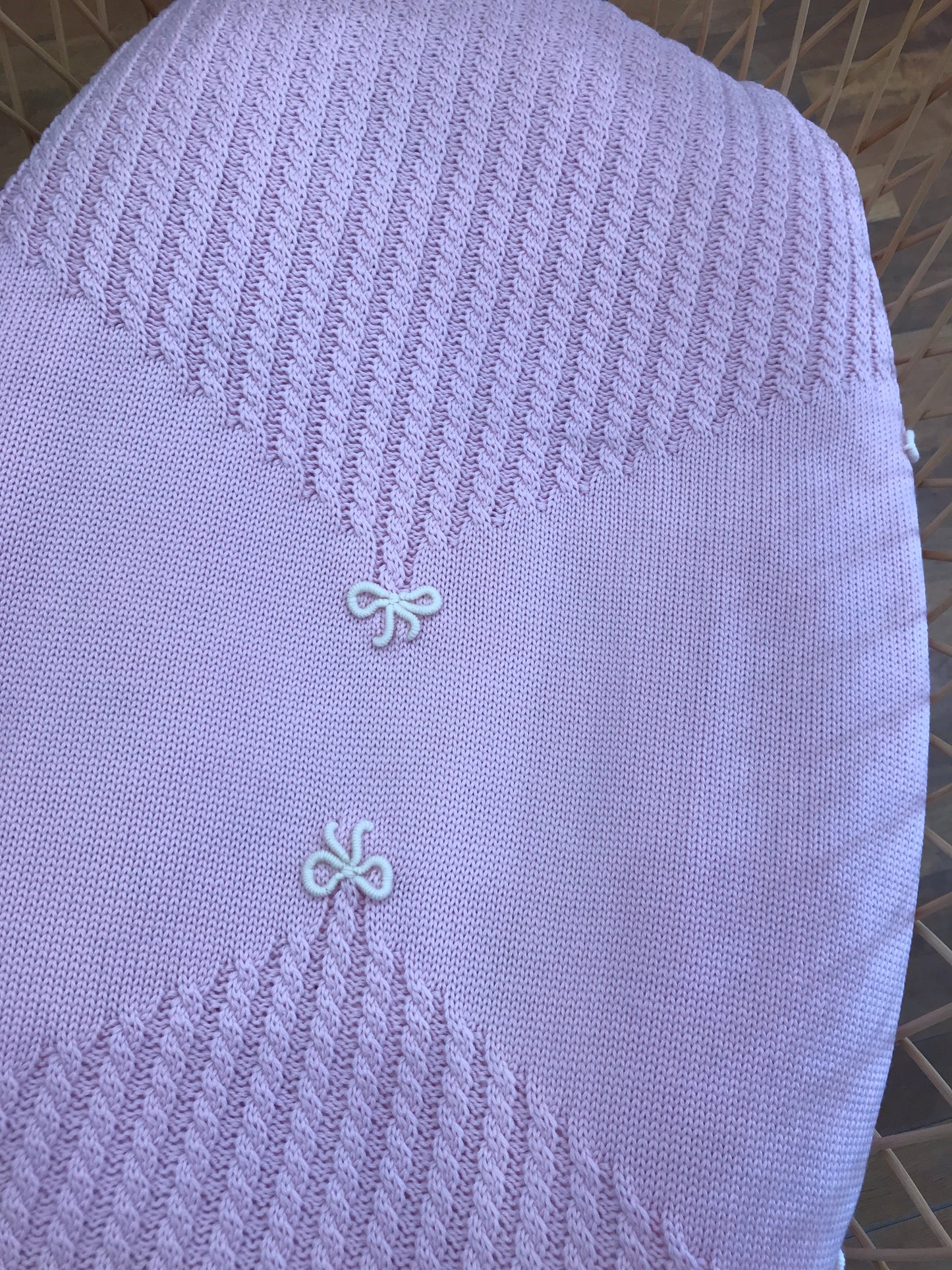 Coperta Bebè di Almy rosa con lavorazione di trecce e piccoli fiocchetti panna