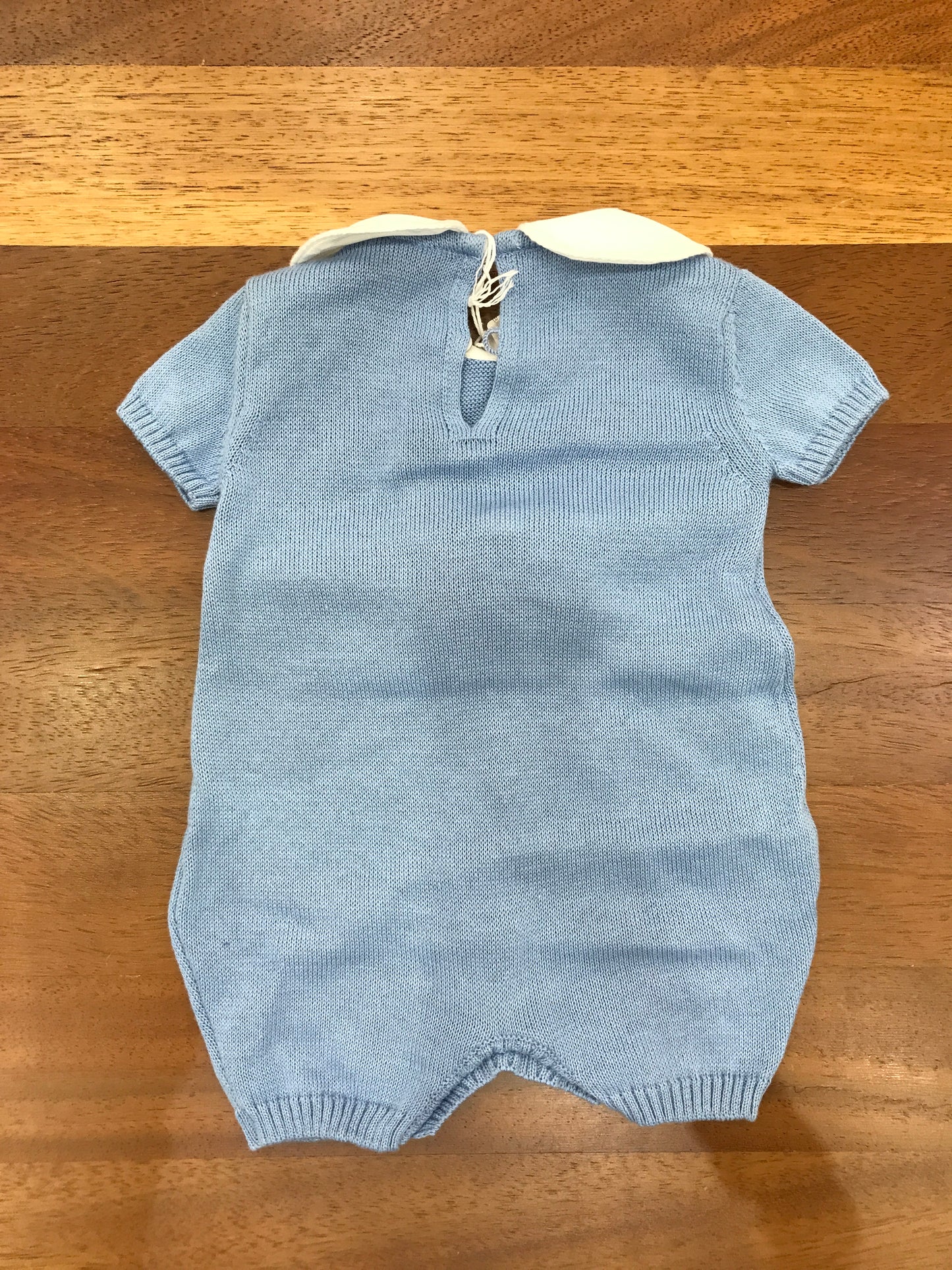 Pagliaccetto Baby Lord in filo celeste con passanastro e fiocco bianco sul davanti mezza manica collo tondo bianco