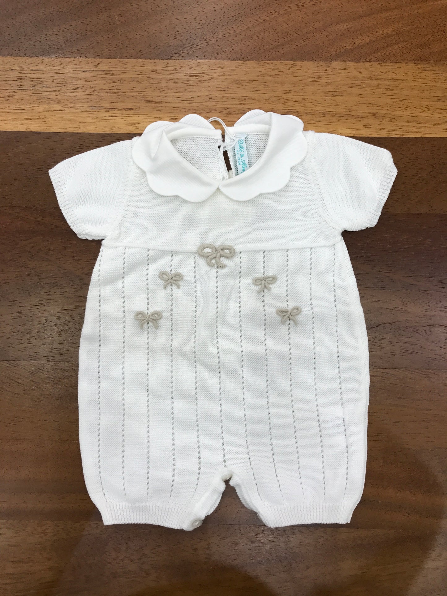 Pagliaccetto Bebè di Almy in filo mezza manica traforato sul davanti con piccoli fiocchi tortora ricamati sul davanti