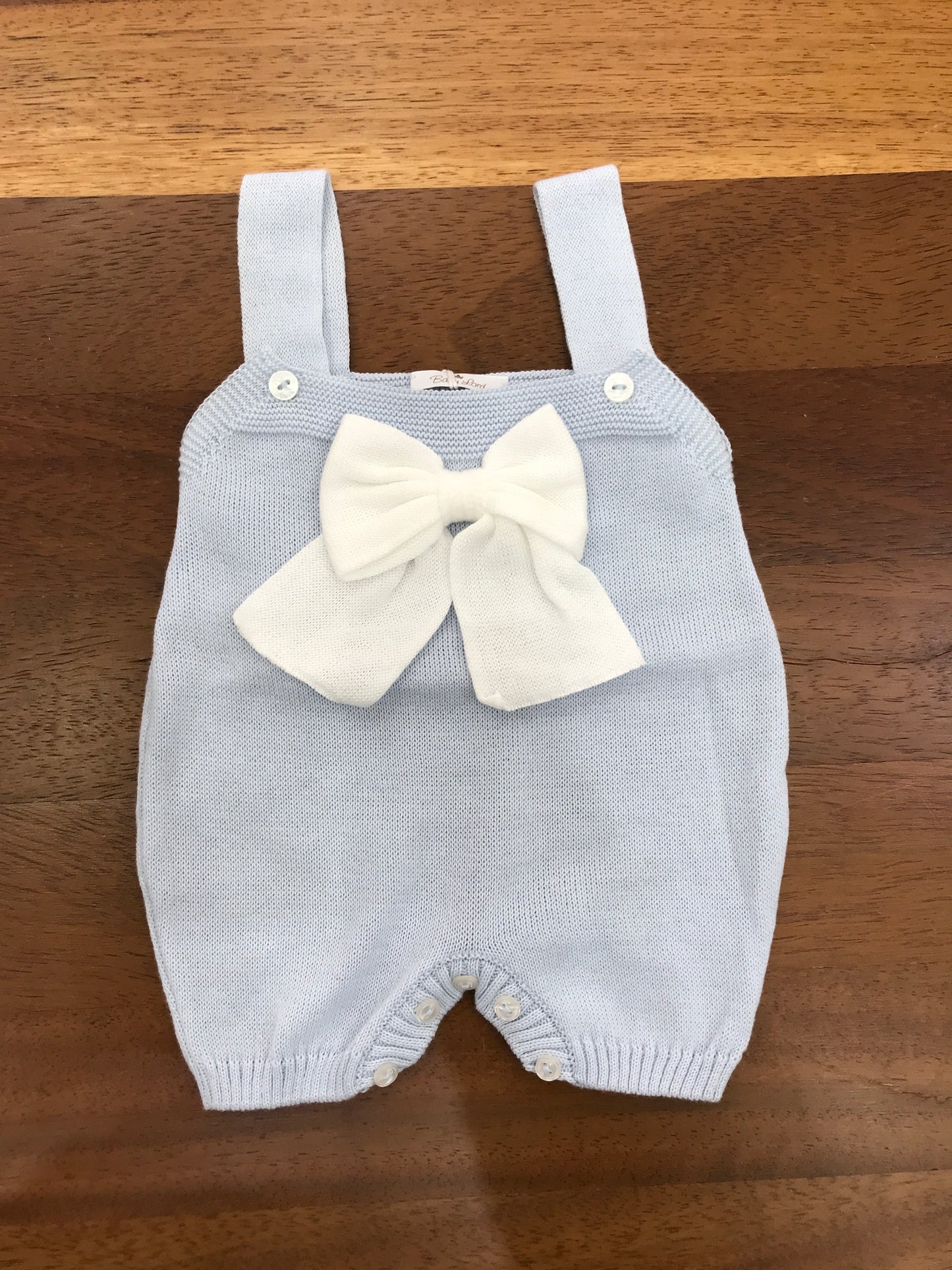 Salopette Baby Lord in filo celeste con bretelle con fiocco bianco centrale