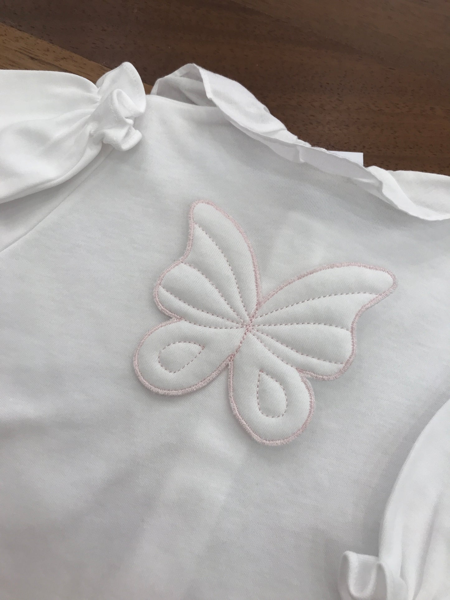 Tutina Baby Gi in cotone con piedini manica lunga con collo con rusche bianca sul retro applicata una farfalla
