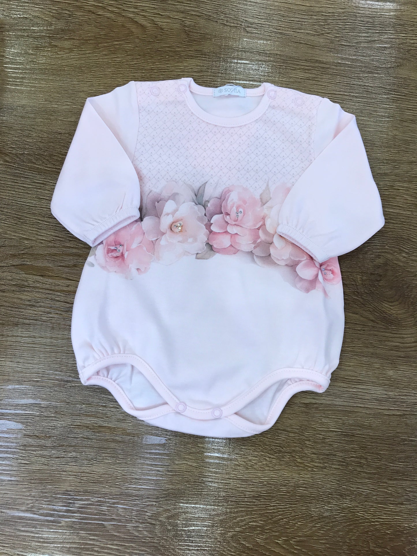 Pagliaccetto Sofija in caldo cotone rosa con camelie sul davanti