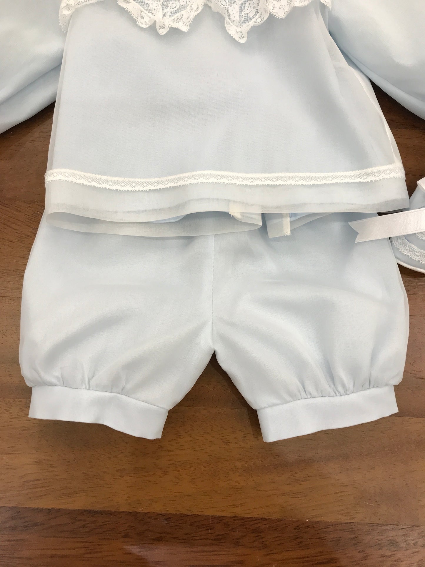 Completo Piccola Giuggiola in organza celeste manica lunga lavorazione in pizzo con e roselline ricamate tutto coordinato ad una cuffia e babbucce
