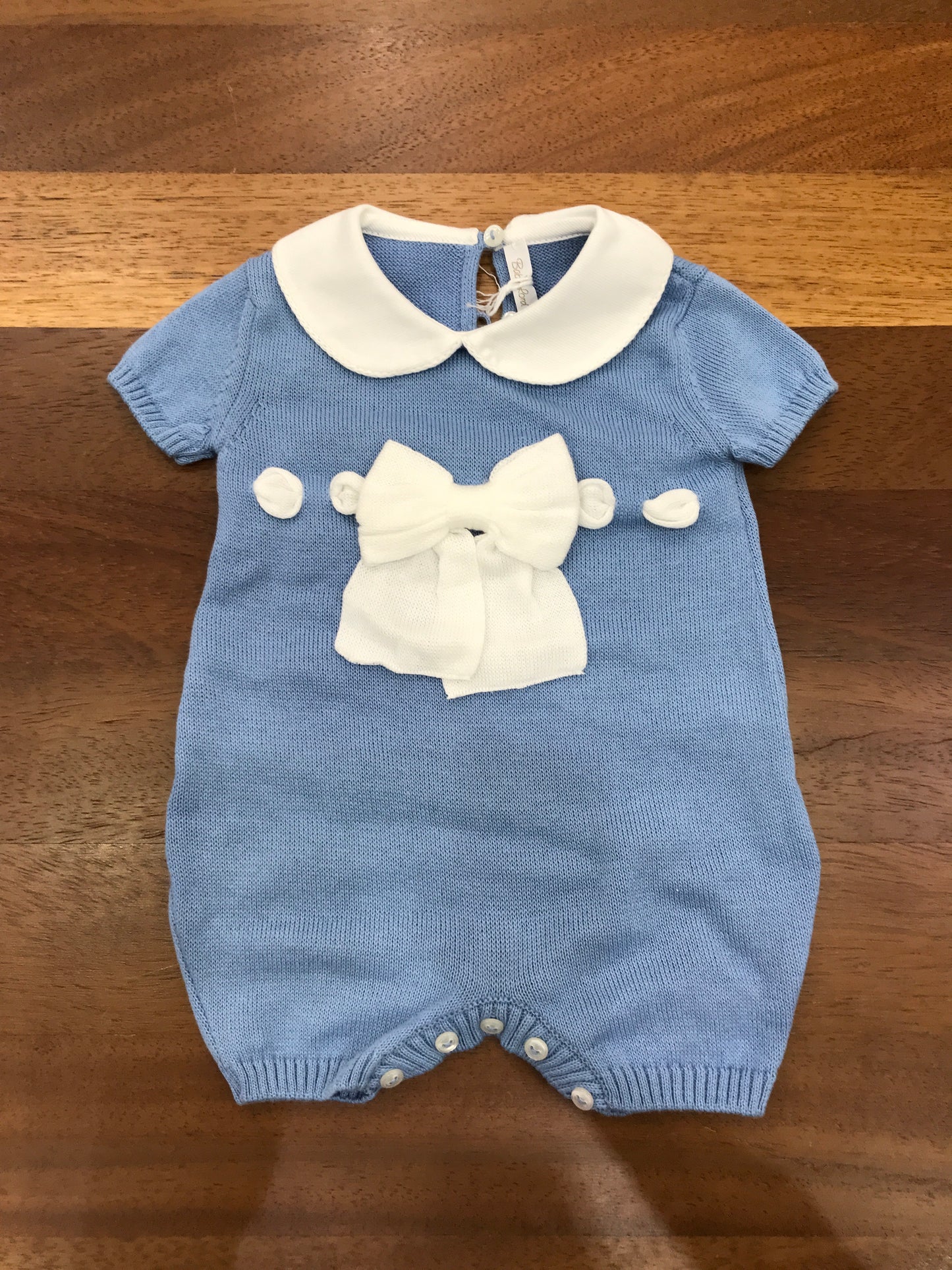 Pagliaccetto Baby Lord in filo celeste con passanastro e fiocco bianco sul davanti mezza manica collo tondo bianco