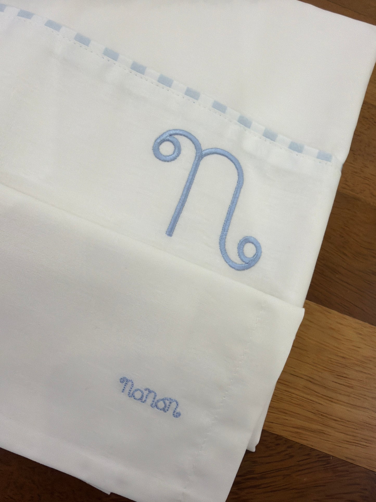Lenzuolino Nanan bianco in cotone con logo nanan su federa con passanastro celeste