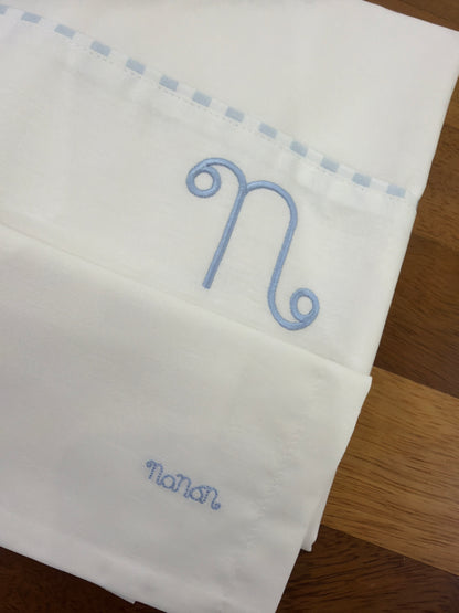 Lenzuolino Nanan bianco in cotone con logo nanan su federa con passanastro celeste