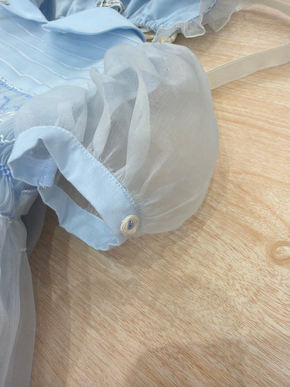 Abito Piccola Giuggiola in organza in seta celeste mezza manica con lavorazione di punto smock e lavorazione di fiori con cuffietta abbinata