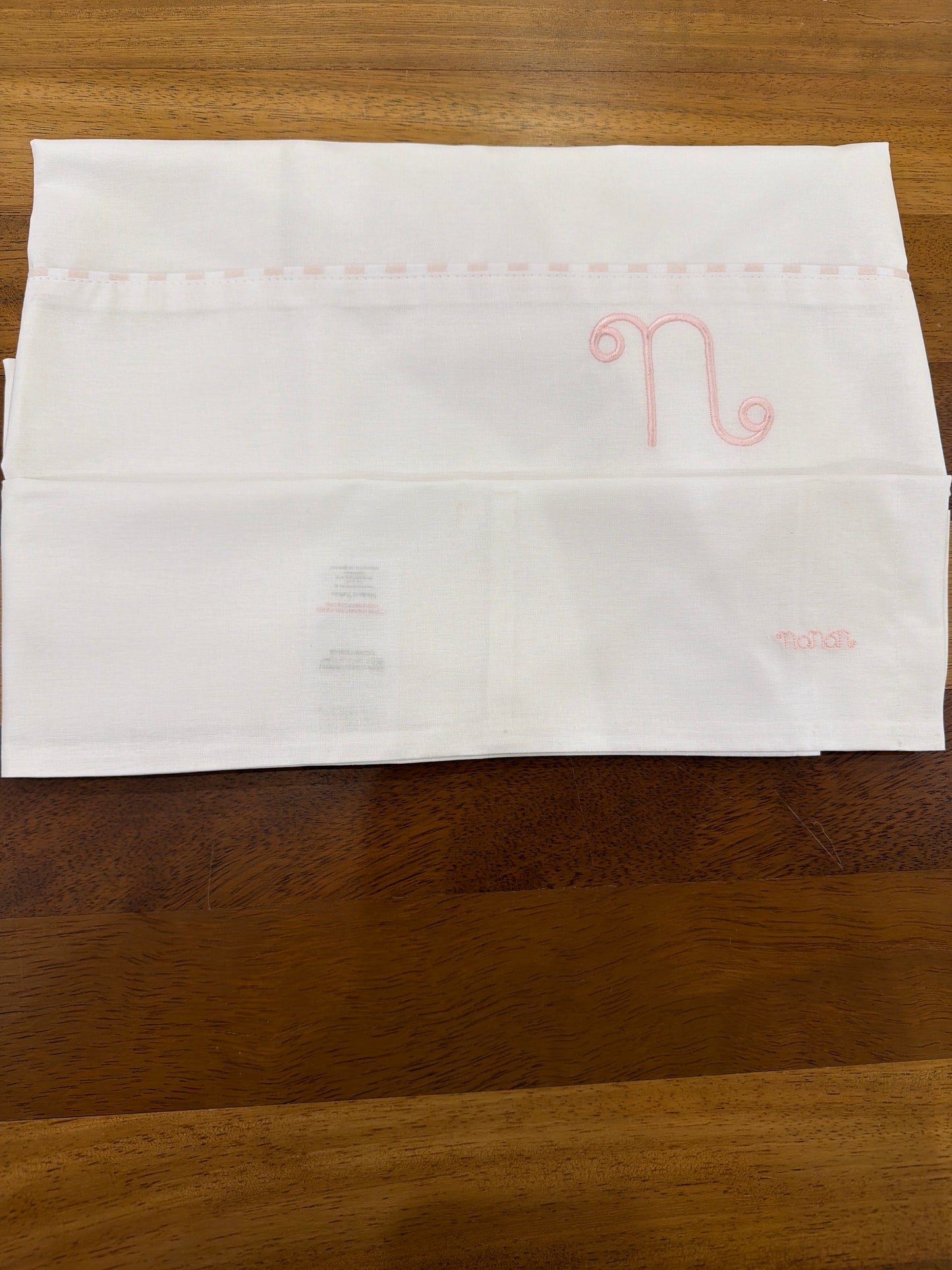 Lenzuolino Nanan in cotone bianco e rosa con logo nanan ricamato su federa  passanastro su lenzuolino rosa