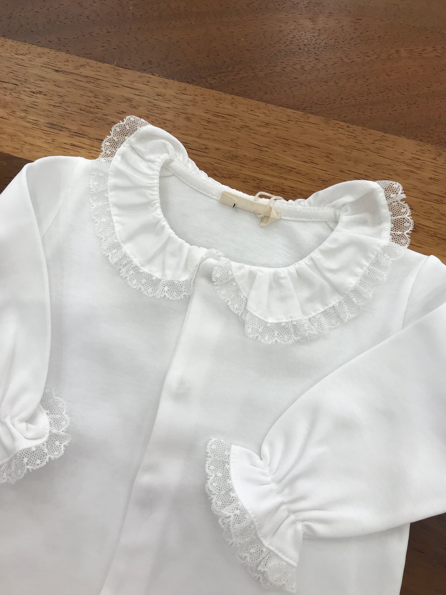Tutina Baby Gi in cotone bianco manica lunga gamba lunga con piedini con collo con rusche rifinita da pizzo