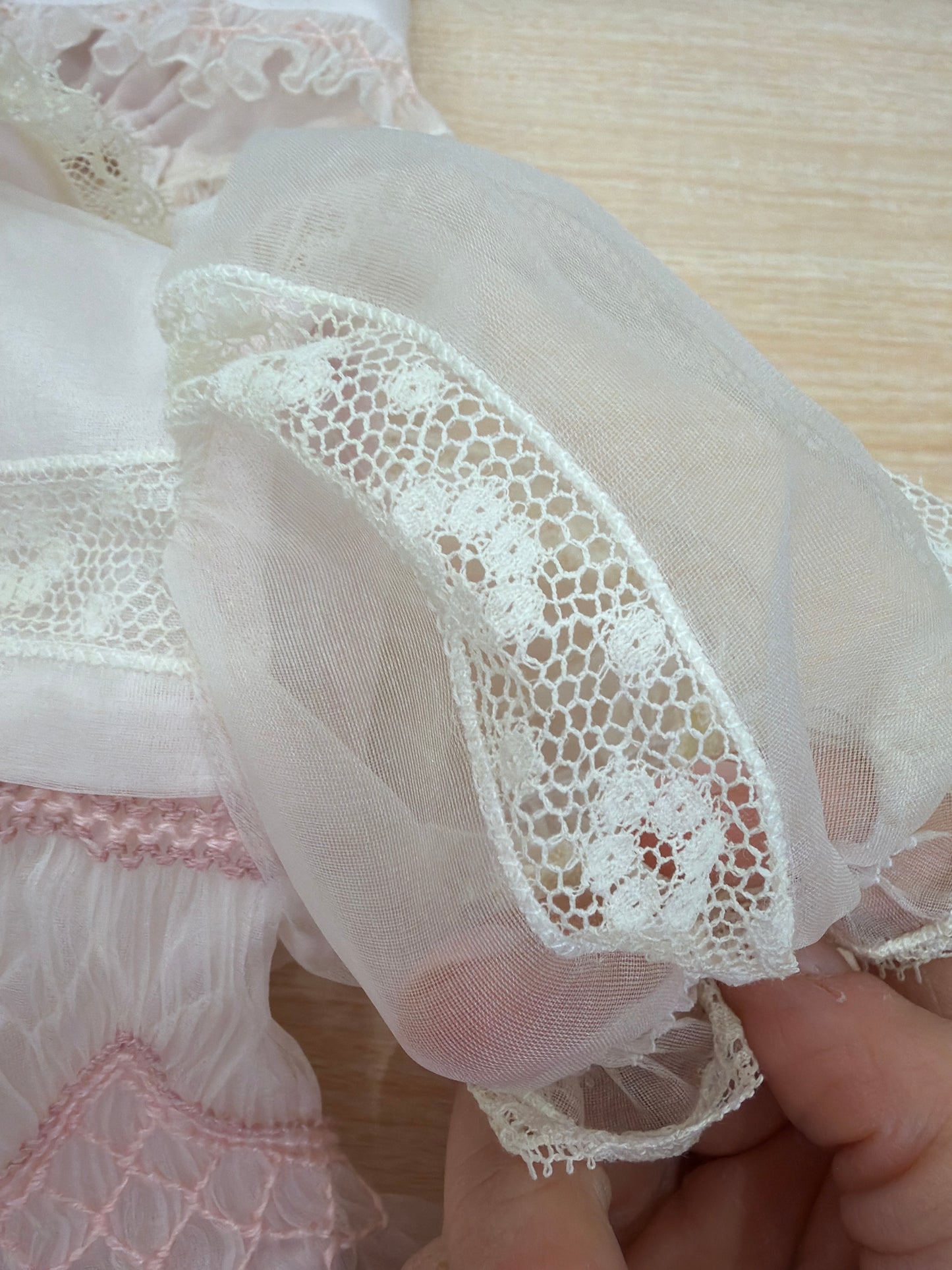 Abito Piccola Giuggiola in organza in seta rosa con applicazione di pizzo sul gonnellone e corpetto con lavorazione di punto smock e fiori ricamati con cuffietta abbinata