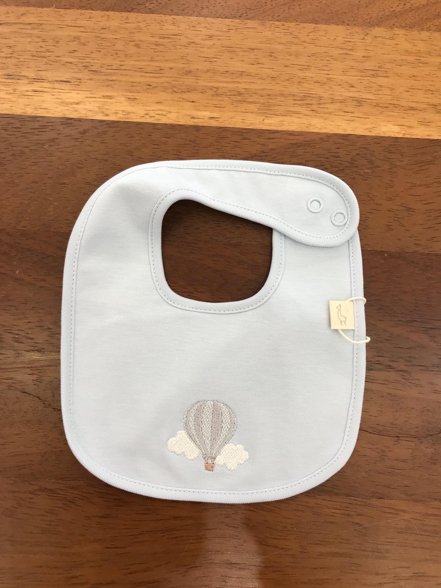 Bavetta Baby Gi in cotone color carta da zucchero con mongolfiera e nuvolette ricamate sul davanti
