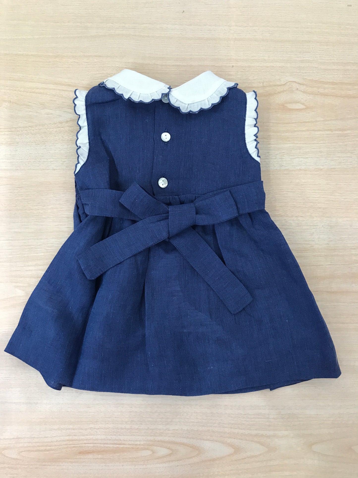 Abito Les Enfants de Gisele in lino smanicato con rusche bianche con colletto bianco e rusche rifinita in blu con corpetto lavorato da punto smock e fiorellini bianchi ricamati