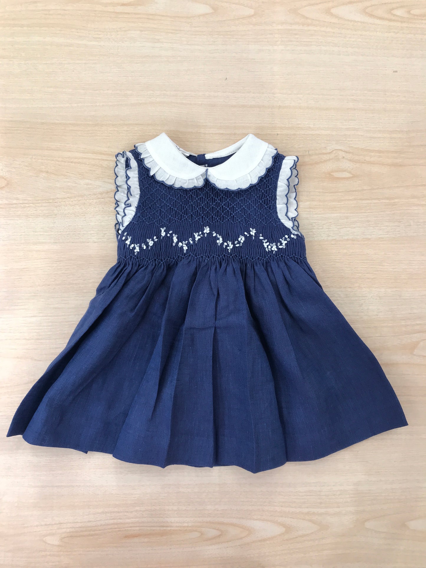 Abito Les Enfants de Gisele in lino smanicato con rusche bianche con colletto bianco e rusche rifinita in blu con corpetto lavorato da punto smock e fiorellini bianchi ricamati