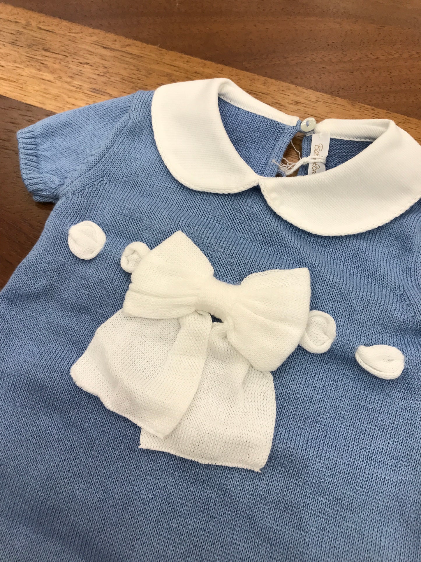 Pagliaccetto Baby Lord in filo celeste con passanastro e fiocco bianco sul davanti mezza manica collo tondo bianco