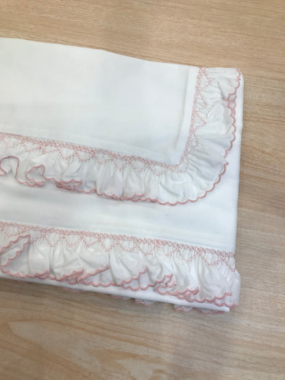 Lenzuolino Colibrì in battista di cotone bianco con rusche ai bordi rosa e lavorazione di punto smock