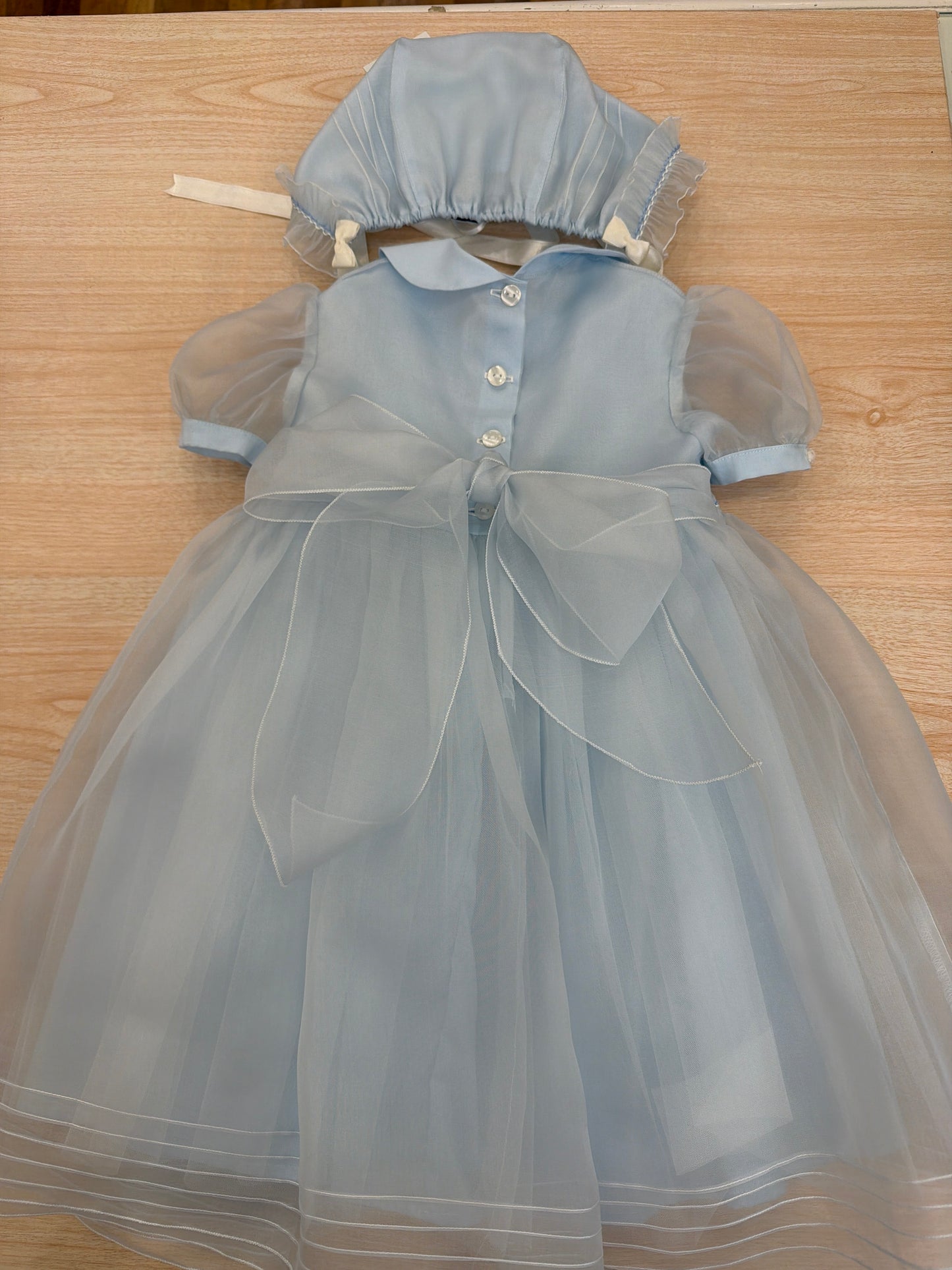 Abito Piccola Giuggiola in organza in seta celeste mezza manica con lavorazione di punto smock e lavorazione di fiori con cuffietta abbinata
