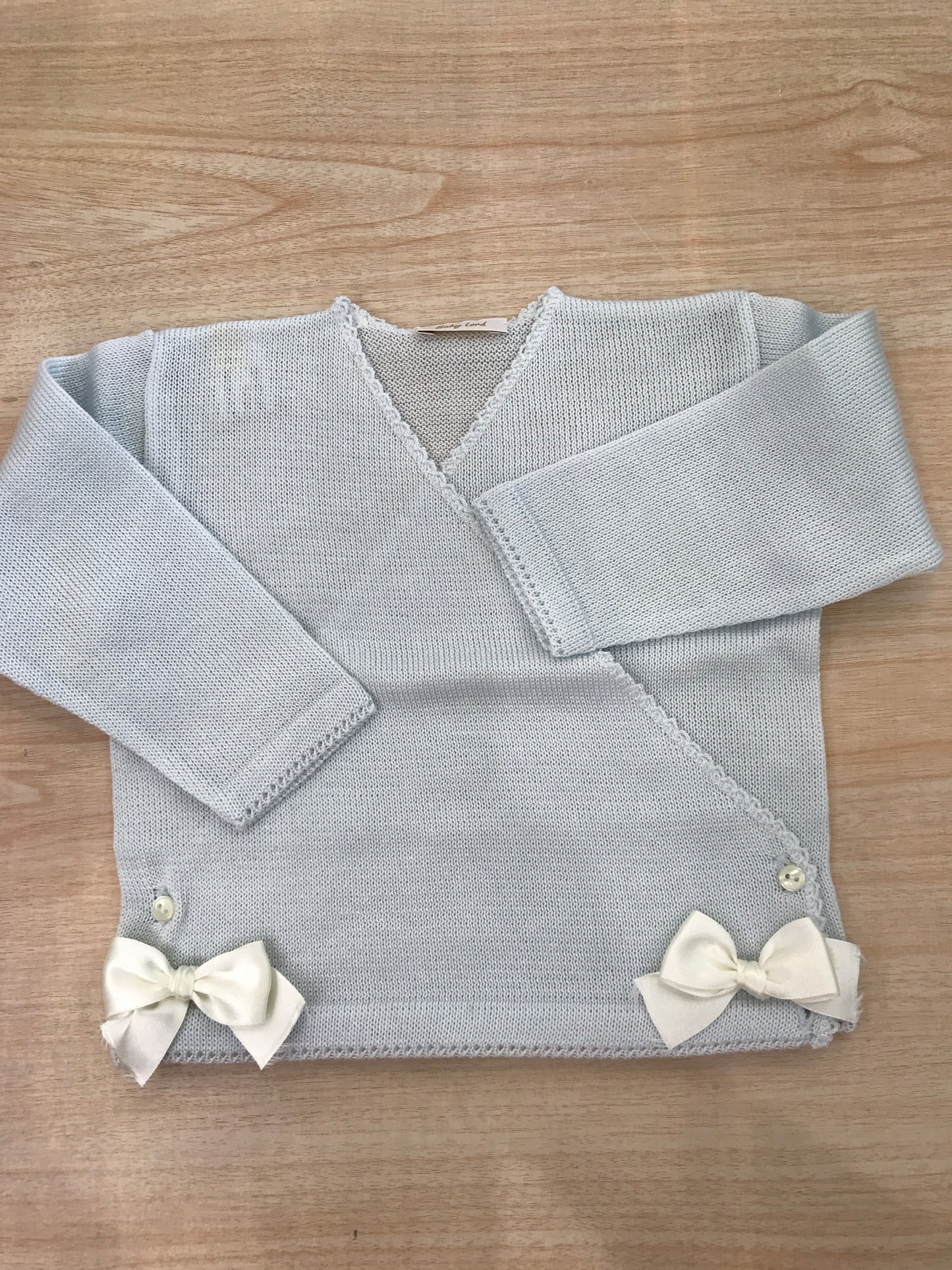 Cardigan Baby Lord in filo celeste ad incrocio con fiocchetti bianchi