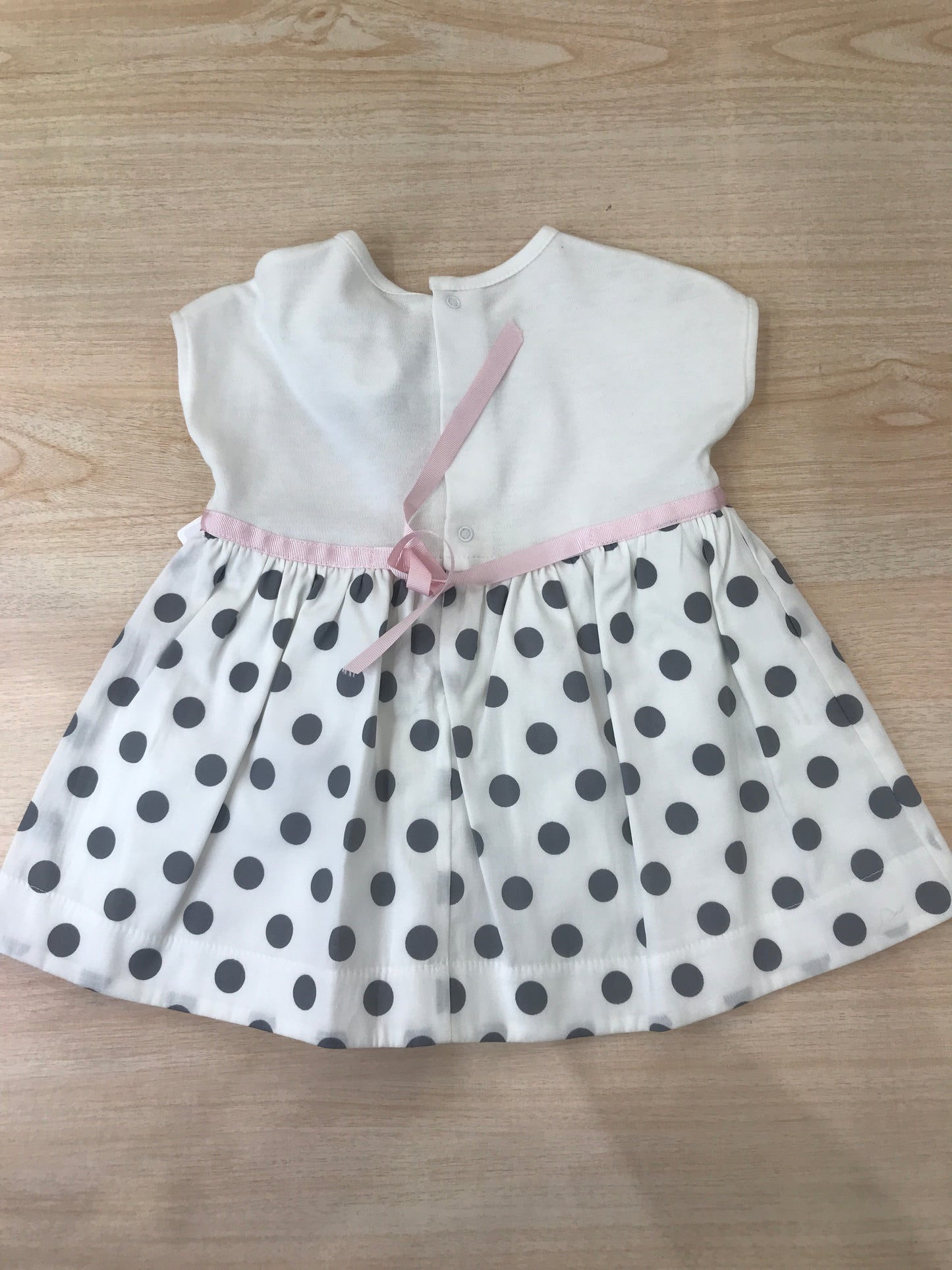 Abito Cielo Blu in cotone con gonna bianca con pois neri con fiori applicati lateralmente e fiocco rosa in vita con culotte abbinata